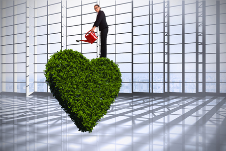 Businesswoman using red watering can against room with large window overlooking cityの写真素材