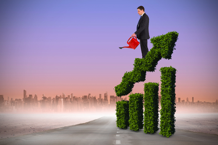 Businessman holding red watering can against road leading out to the horizonの写真素材
