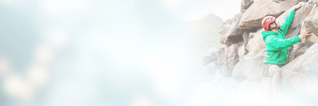 Focused man scaling a large rock face with mountains in the backgroundの写真素材