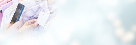 Cropped image of woman scanning bar code with her mobile phone in clothes storeの写真素材