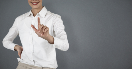 Mid section of smiling businesswoman using invisible screen against grey backgroundの写真素材
