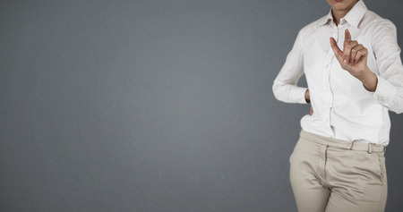 Mid section of businesswoman using invisible screen against grey backgroundの写真素材