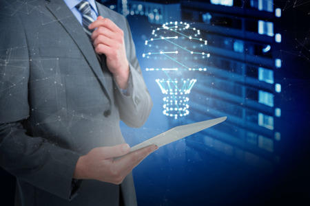 Businessman holding digital tablet against illuminated buildings in city at nightの写真素材