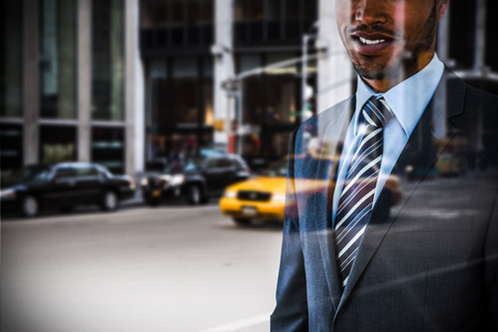 Smiling businessman standing against white background against picture of a city
