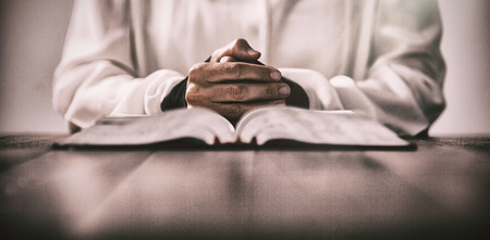 Mid section of woman sitting at desk with bible against gray background
