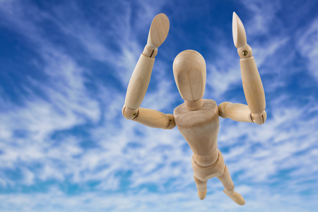 3d image of carefree wooden figurine with arms raised standing  against view of the blue skyの写真素材