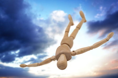 Wooden 3d figurine lying on floor with arms spread against cloudy skyの写真素材