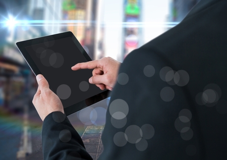 Digital composite of Man over shoulder with tablet against blurry street with flares and bokehの写真素材