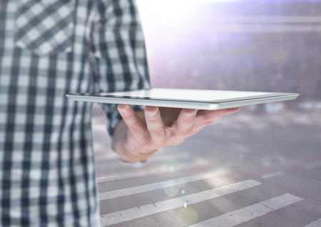 Digital composite of Man mid section with tablet against blurry street with flaresの写真素材