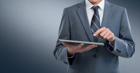 Digital composite of Business man mid section with tablet against navy backgroundの写真素材