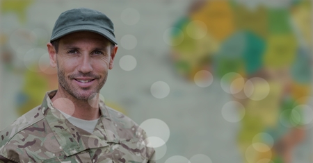 Digital composite of Soldier smiling against blurry map with bokeh