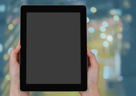 Digital composite of Hand holding a tablet over night city lightsの写真素材