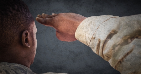 Digital composite of Back of soldier saluting against grey background with grunge overlayの写真素材