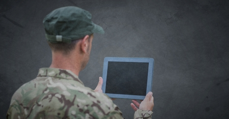 Digital composite of Back of soldier with tablet against grey background with grunge overlayの写真素材