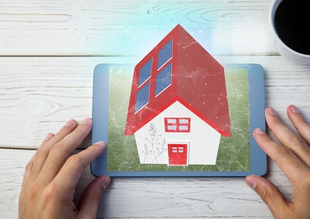 Digital composite of red roof house on tablet. with tableの写真素材