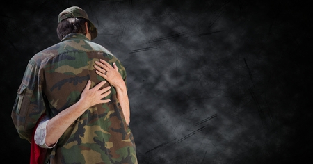 Digital composite of Back of soldier being hugged against black grunge backgroundの写真素材