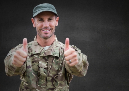 Digital composite of Soldier thumbs up against grey wall