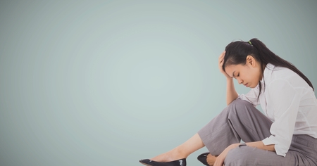 Digital composite of Business woman sitting with head on hand against light blue backgroundの写真素材