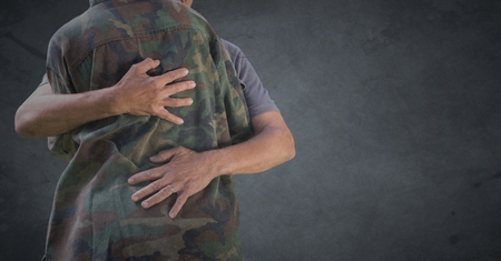 Digital composite of Back of soldier hugging against grey background with grunge overlayの写真素材