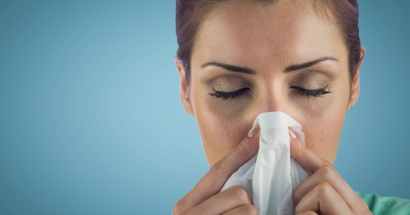 Digital composite of Close up of woman blowing nose against blue backgroundの写真素材
