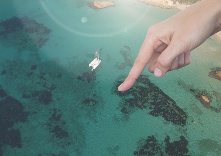 Digital composite of Hand pointing in air over sunny seaside resortの写真素材