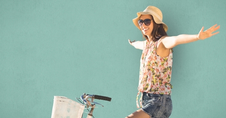 Digital composite of Young woman with arms outstretched riding bicycleの写真素材