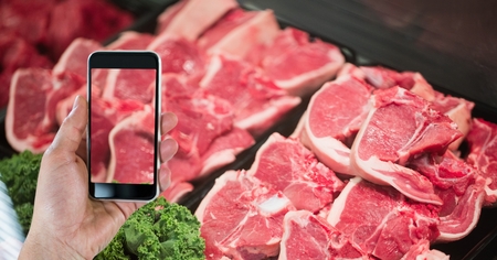 Digital composite of Hand photographing meat through smart phone in grocery storeの写真素材