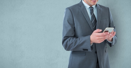 Digital composite of Midsection of businessman using mobile phone over blue backgroundの写真素材
