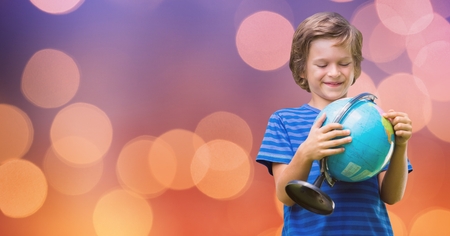 Digital composite of Smiling boy holding globe over bokehの写真素材