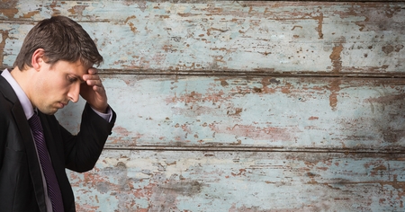 Digital composite of Businessman suffering from headache over wooden wallの写真素材