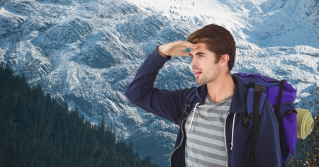 Digital composite of Male hiker shielding eyes while carrying backpack on mountainの写真素材