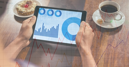 Digital composite of Hands holding digital tablet displaying graphs with overlay