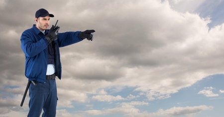 Digital composite of Security guard using radio against cloudy skyの写真素材