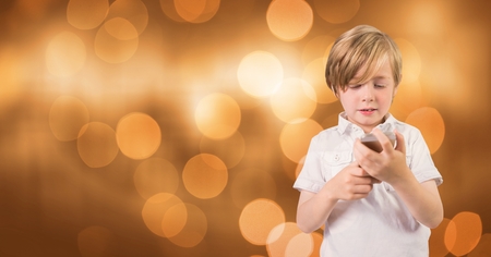 Digital composite of Little boy holding mobile phone over bokehの写真素材
