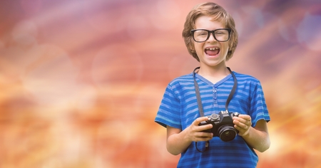 Digital composite of Portrait of cheerful boy holding camera over bokehの写真素材