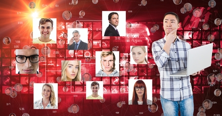 Digital composite of Thoughtful man holding laptop by flying portraits