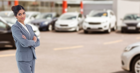 Digital composite of Portrait of businesswoman with arms crossed in car showroomの写真素材