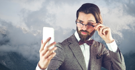 Digital composite of Hipster wearing eyeglasses while reading message on smart phoneの写真素材