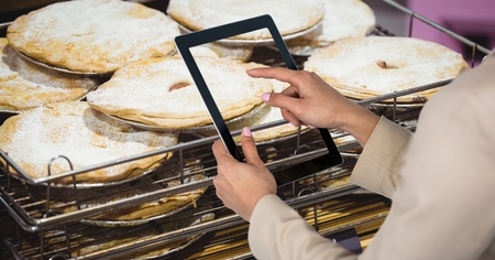 Digital composite of Woman photographing food through tablet computer in grocery storeの写真素材