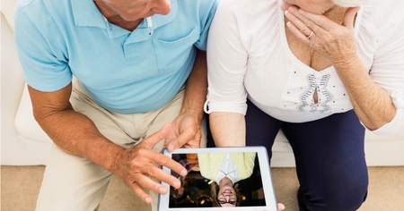 Digital composite of Senior couple video conferencing on tablet PCの写真素材