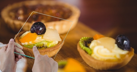 Digital composite of Hands taking picture with transparent device in bakeryの写真素材