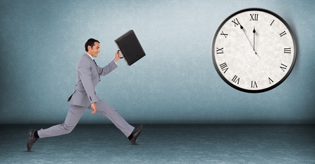 Digital composite of Full length of businessman running late with clock in backgroundの写真素材