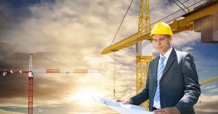 Digital composite of Architect looking at blueprint against craneの写真素材
