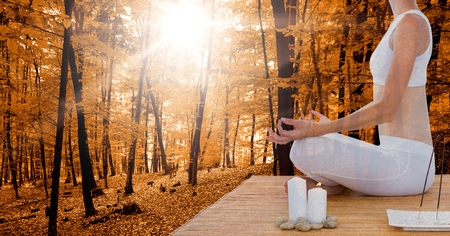 Digital composite of Double exposure of woman meditating in forest during autumnの写真素材