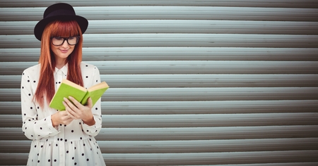 Digital composite of Redhead woman reading book against wallの写真素材