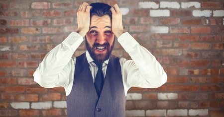 Digital composite of Businessman pulling hair against brick wallの写真素材