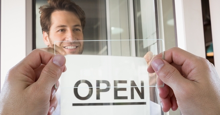 Digital composite of Hands photographing open sign through transparent device while man smiling in...