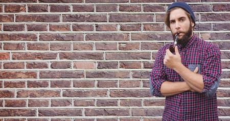 Digital composite of Hipster smoking pipe against brick wallの写真素材