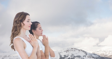 Digital composite of Double exposure of women with hands clasped meditating by snowcapped mountainsの写真素材