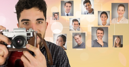 Digital composite of Confident male photographer holding camera against flying portraitsの写真素材